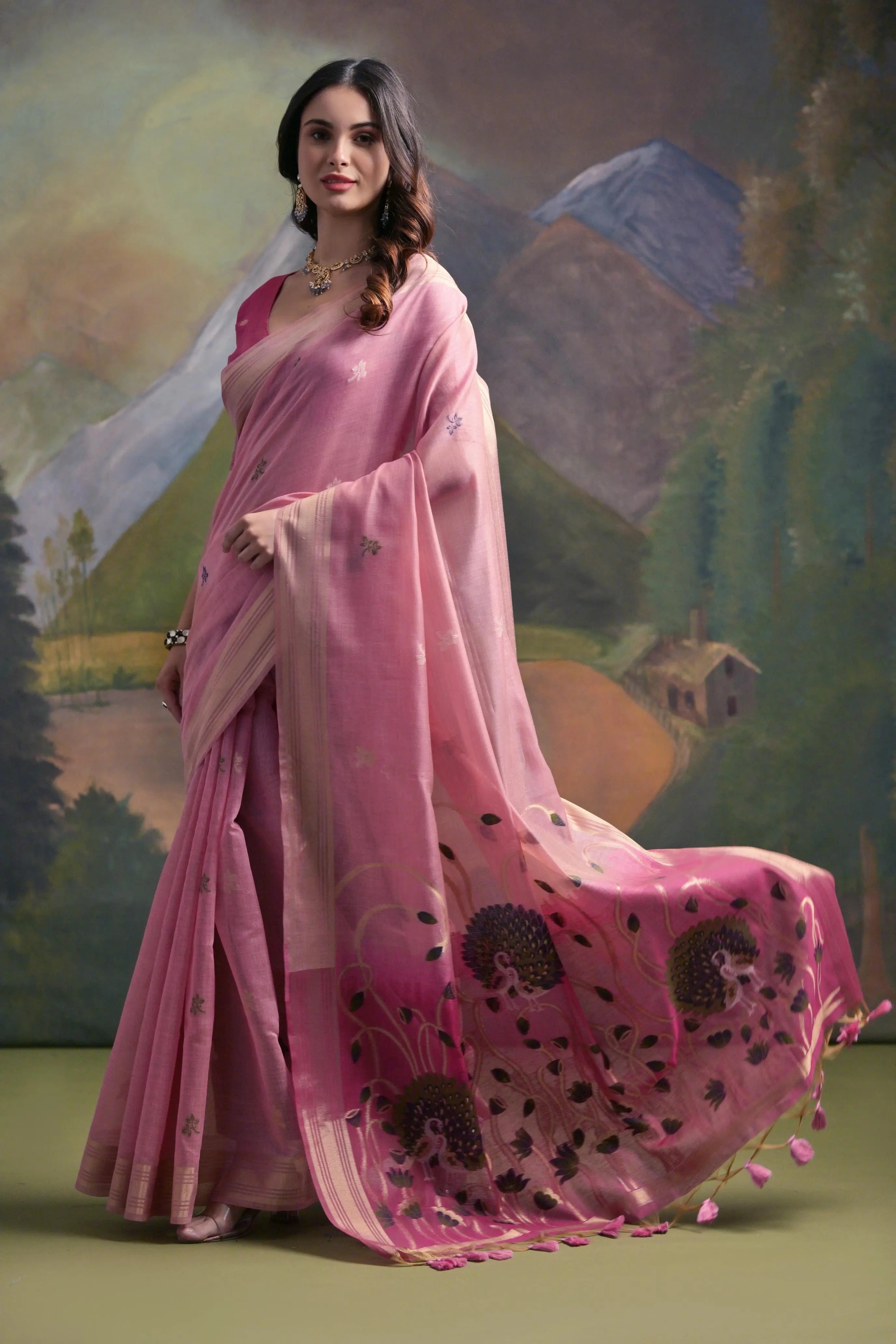 A woman models a vibrant Pink Muga Silk Saree with subtle Resham weaving. The pallu transitions to a darker pink/magenta, featuring intricate purple and green floral Resham threadwork. She wears a matching pink blouse and a gold Kundan necklace.
